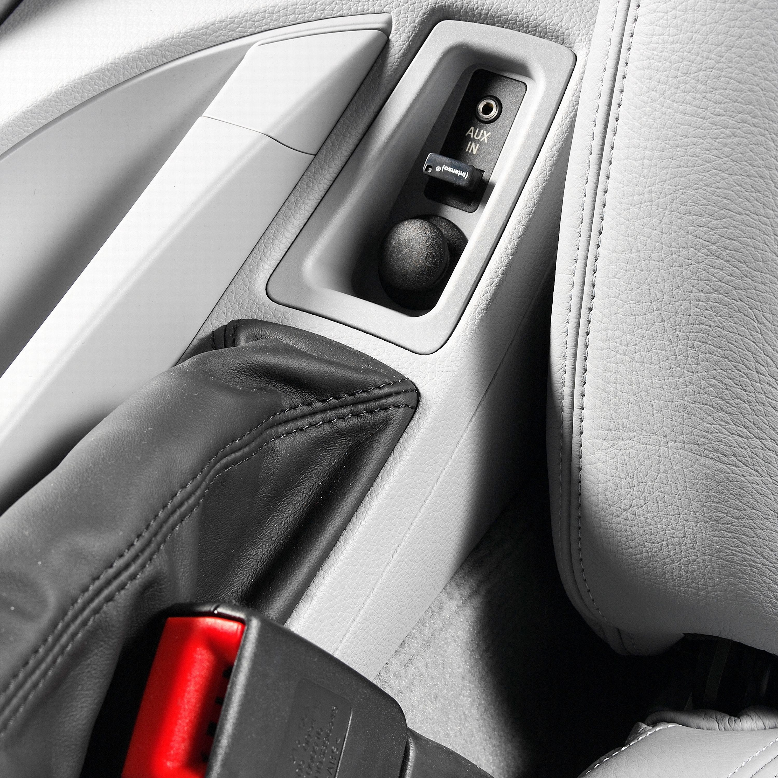 Wnętrze samochodu z gniazdem aux-in, zapalniczką i hamulcem ręcznym.