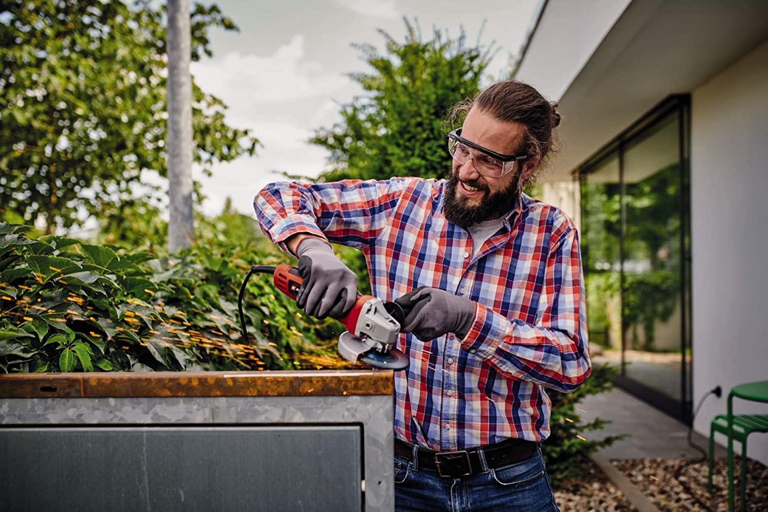 Mężczyzna w okularach ochronnych używa szlifierki kątowej, iskrzy.