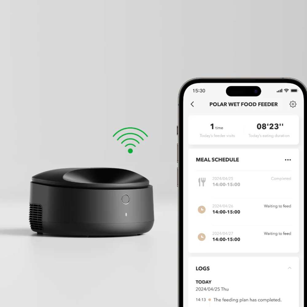 Un comedero negro junto a un smartphone que muestra un horario de alimentación.