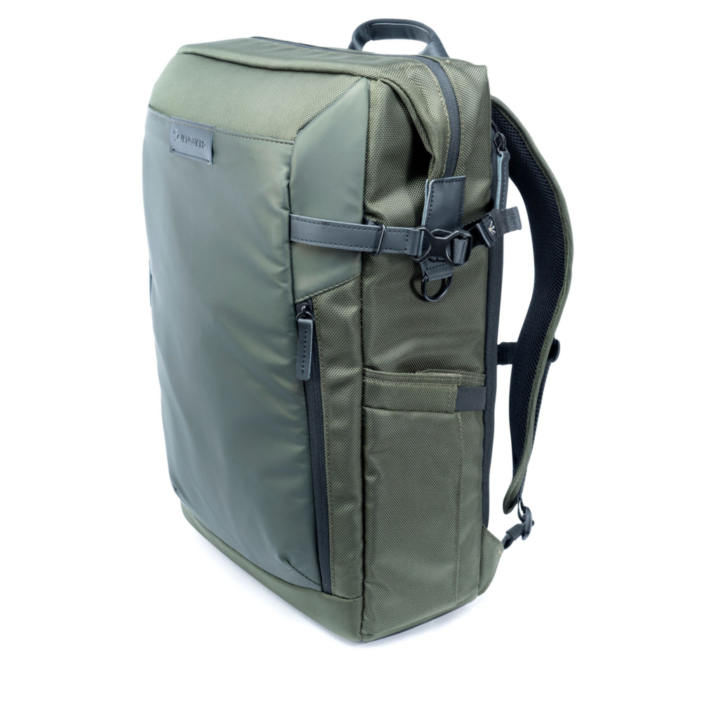 Ein grüner Rucksack mit dunklen Gurten und Reißverschlüssen steht auf weißem Hintergrund.