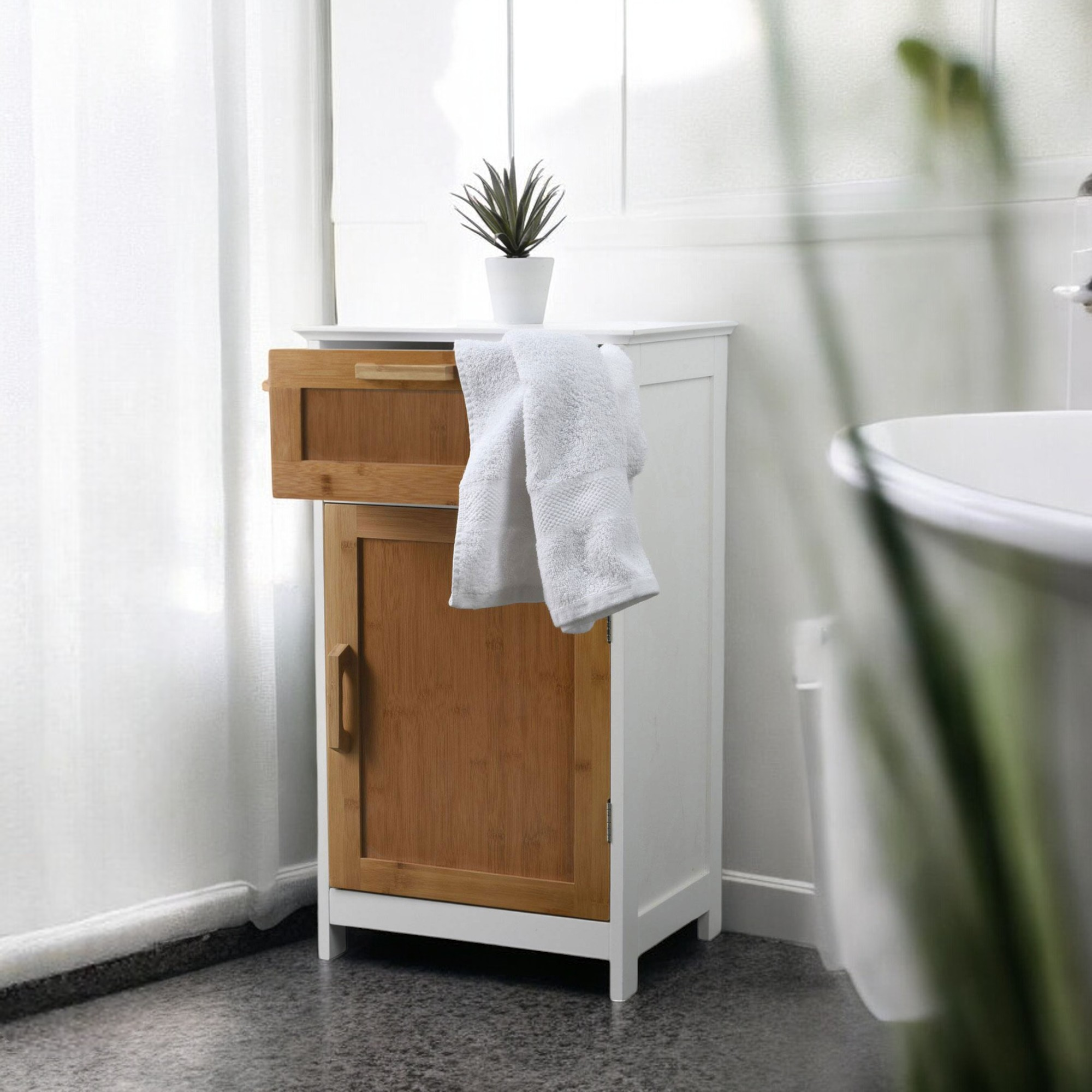 Un mueble de baño blanco con puertas de madera, toalla y planta.