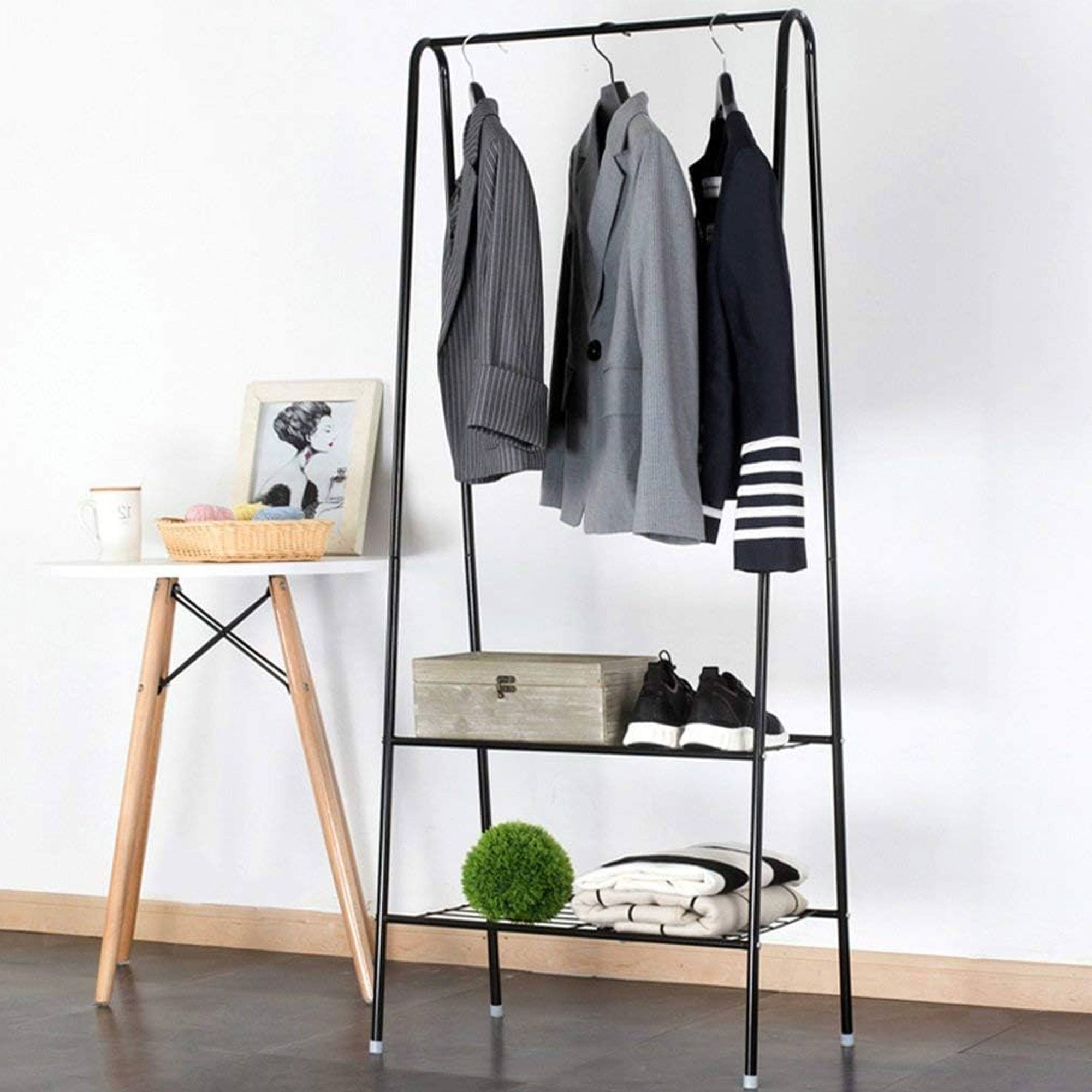 Perchero negro con ropa, zapatos, caja y decoración.
