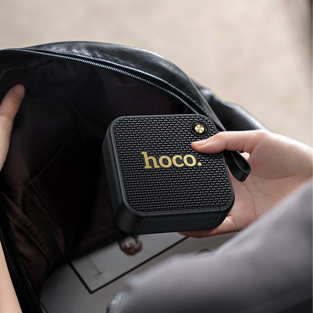 Una persona coloca un altavoz negro hoco en un bolso negro.