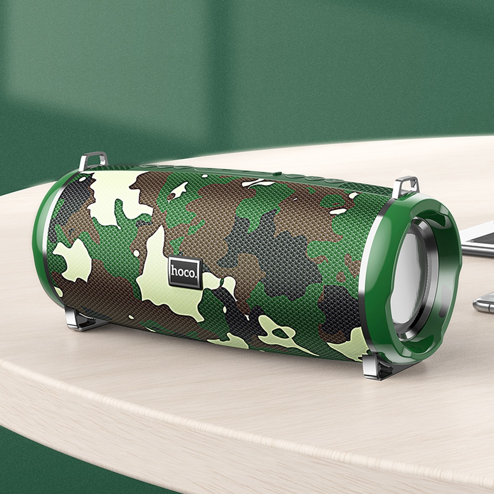 Altavoz de camuflaje con logo Hoco sobre mesa de madera.