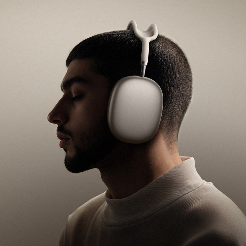 Un hombre con los ojos cerrados lleva auriculares blancos con copas plateadas.