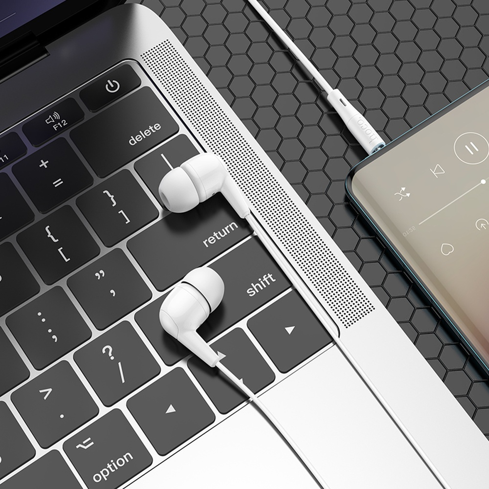 Auricolari bianchi su una tastiera per laptop accanto a uno smartphone che riproduce musica.