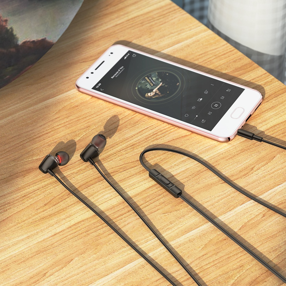 Un teléfono inteligente y auriculares en una mesa de madera. Música sonando en pantalla.