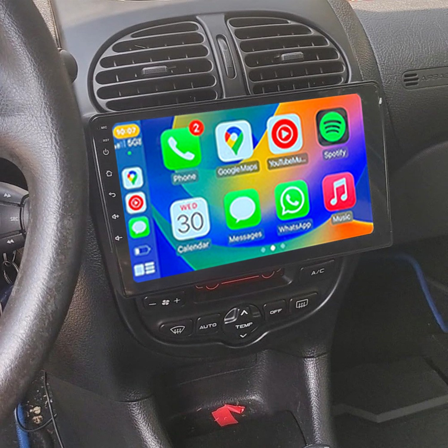 La pantalla táctil de un coche muestra apps como Teléfono, Google Maps y Spotify.