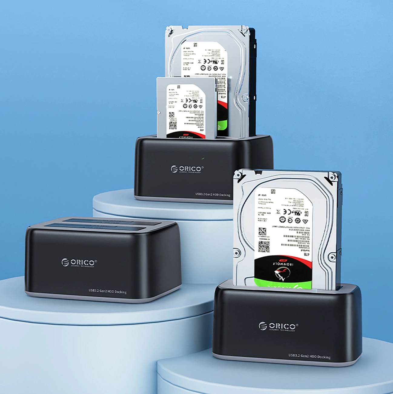 Trzy czarne stacje dokujące ORICO z dyskami twardymi na niebieskich postumentach.