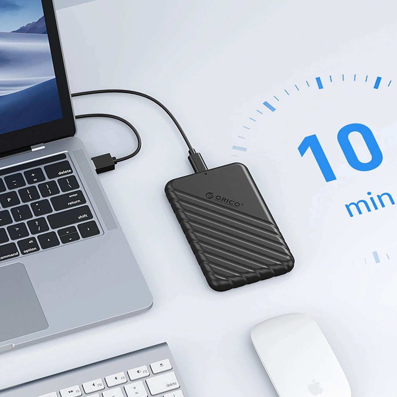 Czarny zewnętrzny dysk twardy podłączony do laptopa, obok mysz i klawiatura.