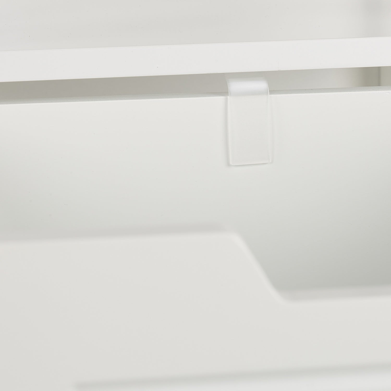 Un clip transparente cuelga de un borde blanco sobre un hueco.