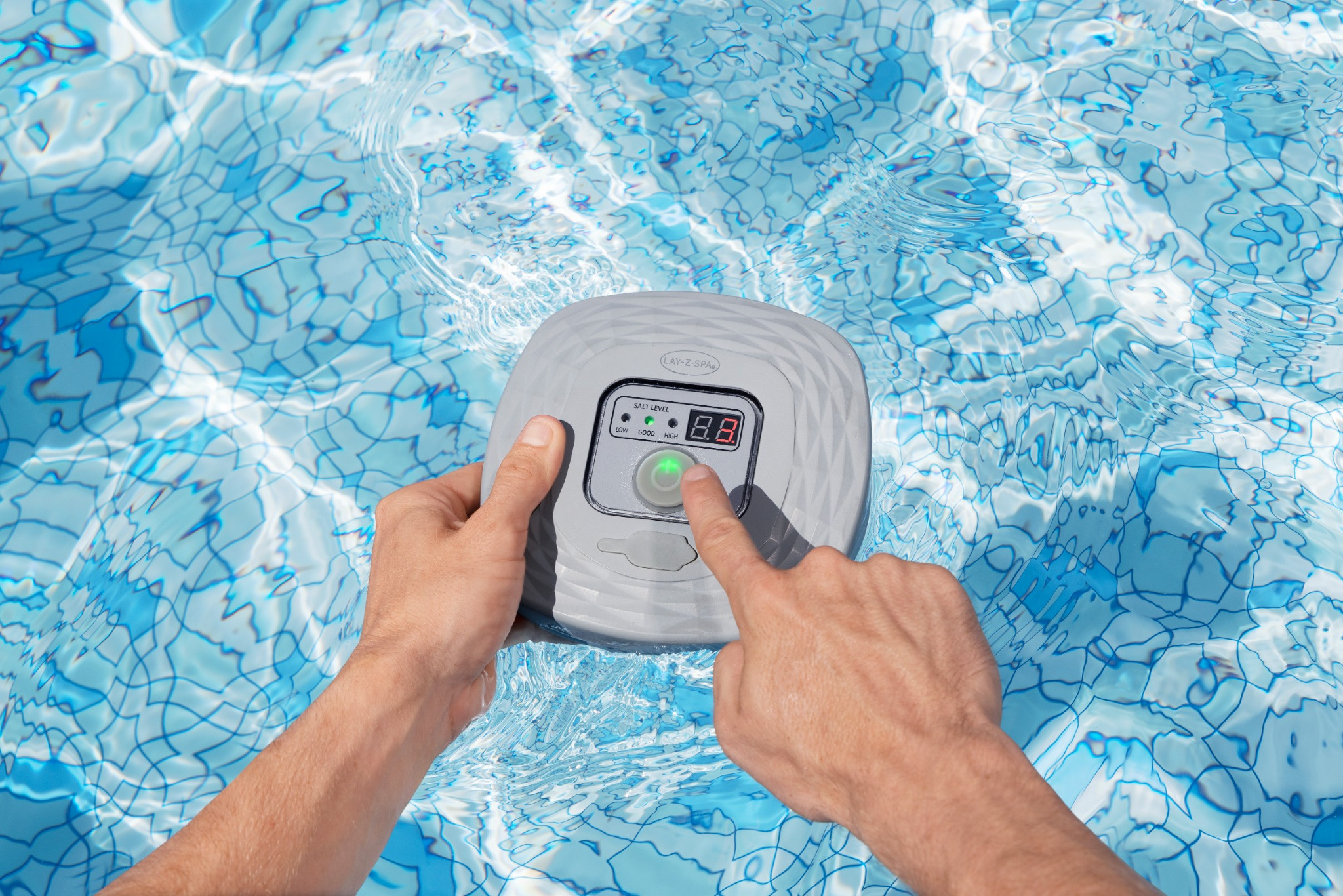 Mani azionano un pannello di controllo di una piscina grigio sott'acqua con piastrelle blu.