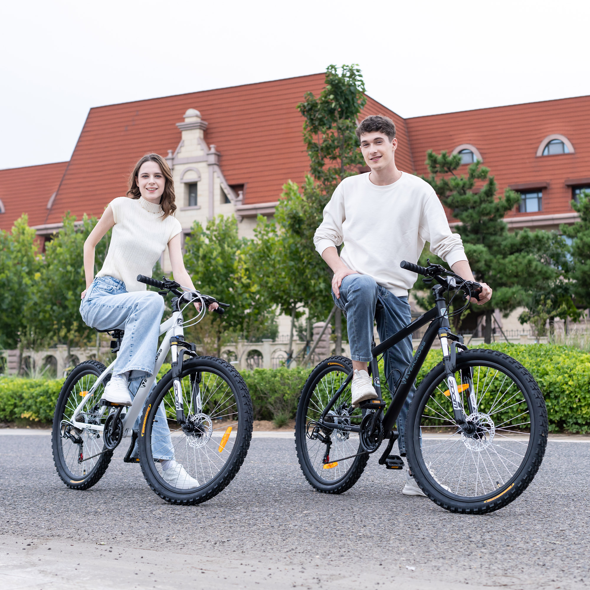 Ein Mann und eine Frau sitzen auf Fahrrädern vor einem Gebäude.