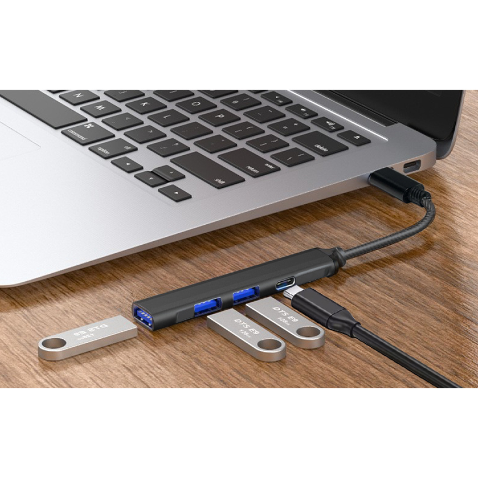 Hub USB con dos memorias conectadas a un portátil, sobre mesa de madera.