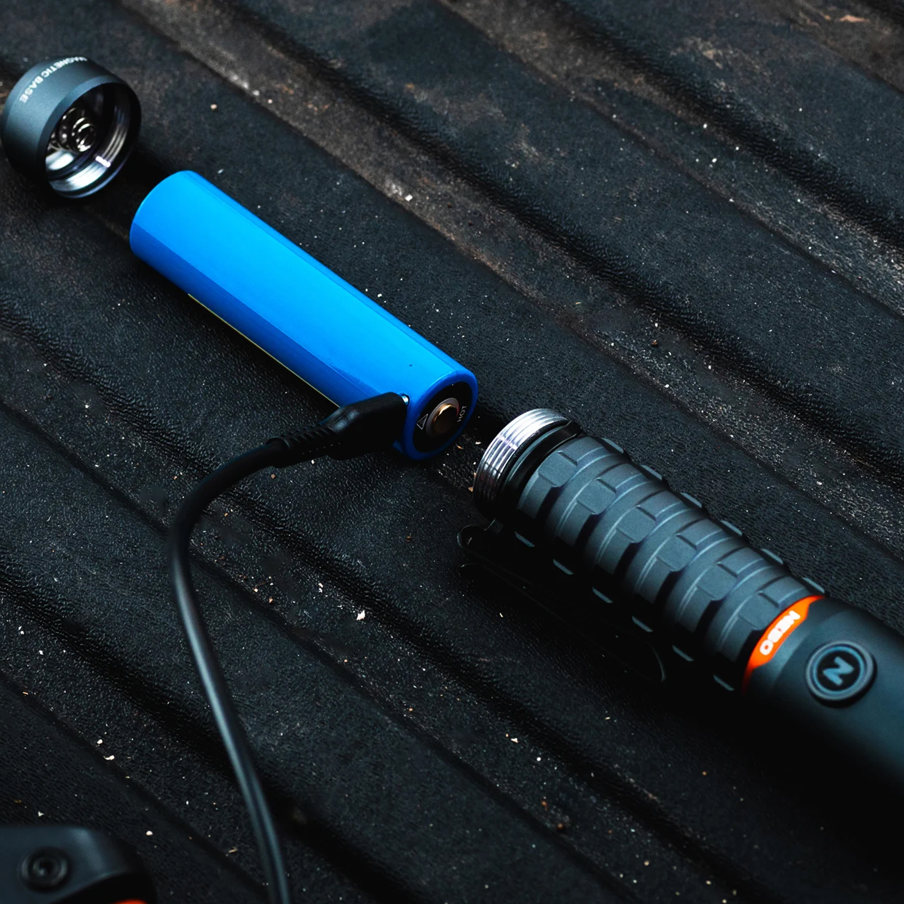 Une batterie bleue est insérée dans une lampe de poche noire.