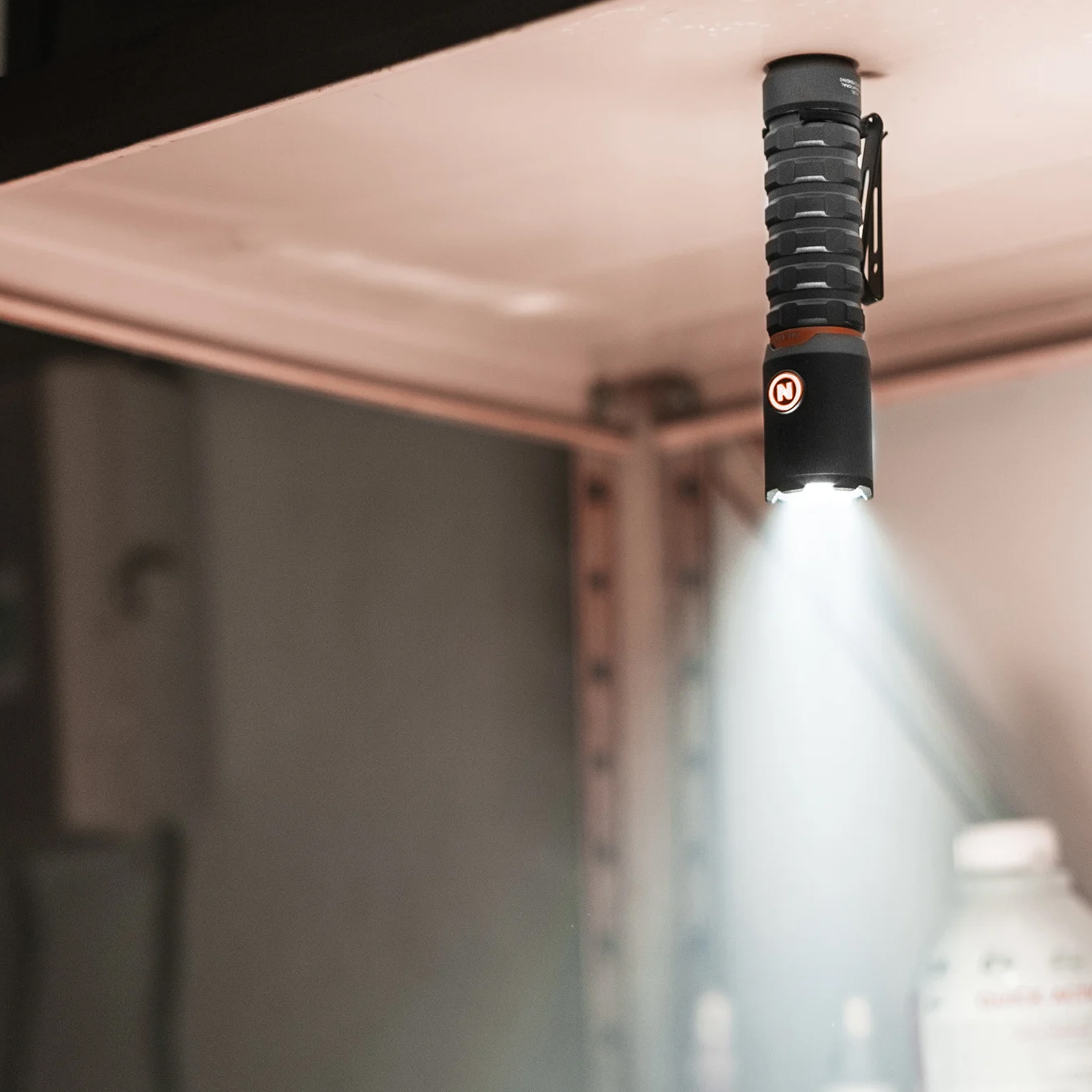 Une lampe de poche noire pend du plafond, émettant de la lumière vers le bas.