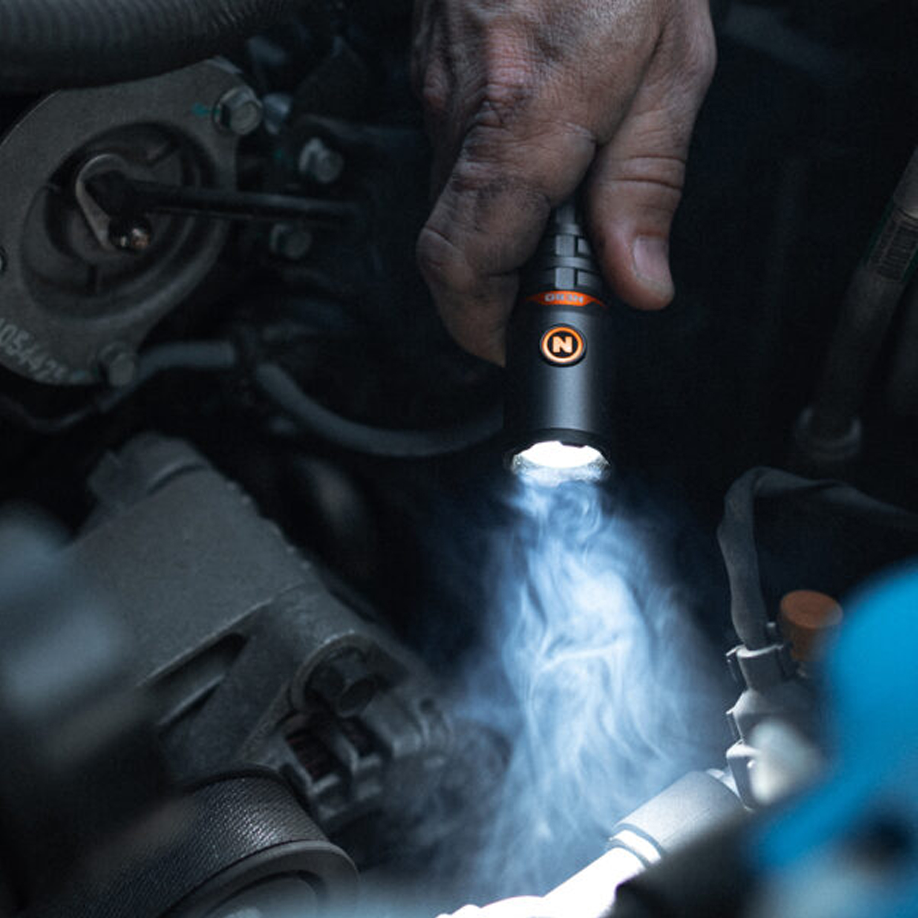 Une main utilise une lampe de poche pour éclairer un moteur.
