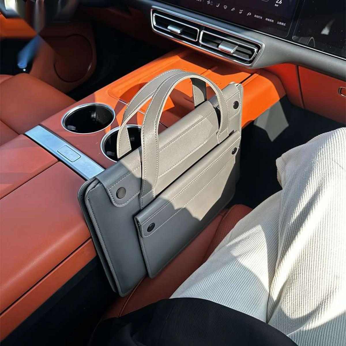 Graue Tasche auf dem Beifahrersitz eines Autos mit orangefarbenen Akzenten.