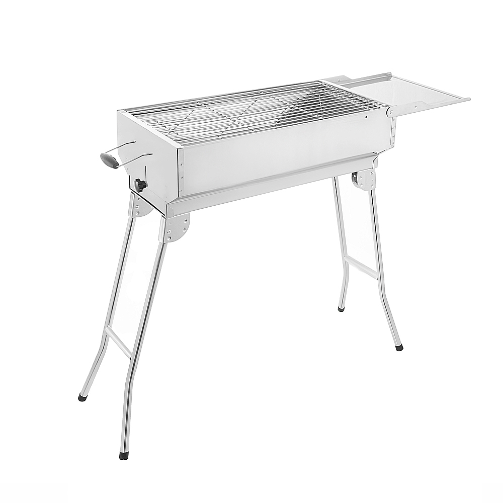 Ein glänzender Metallgrill auf ausklappbaren Beinen, mit einem Rost und einer Seitenablage.