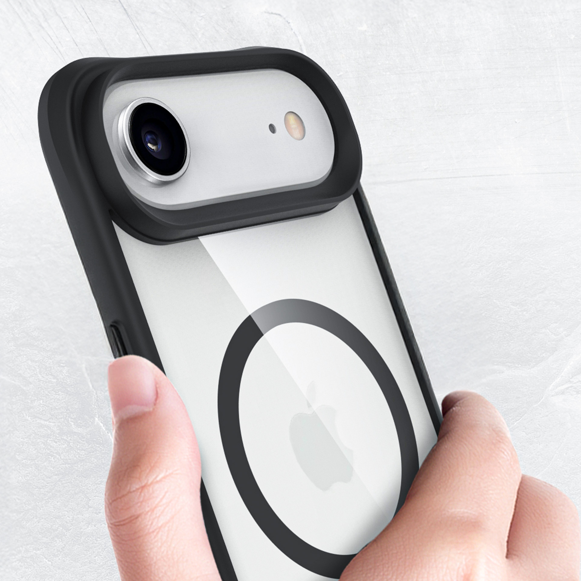Dłoń trzyma iPhone'a w przezroczystym etui z czarnym pierścieniem i logo Apple.