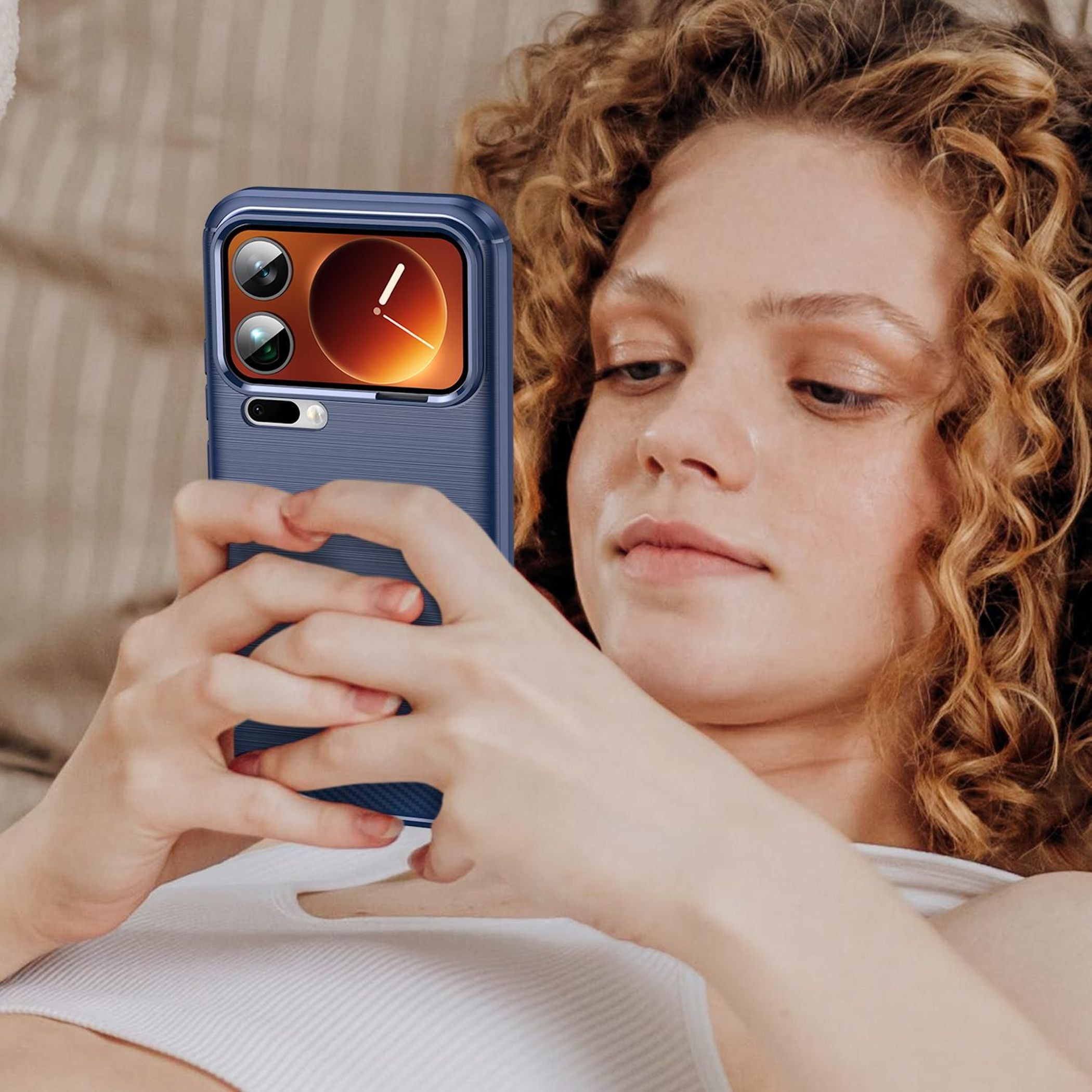 Eine Frau mit lockigem Haar hält ein blaues Smartphone mit Kameramodul.