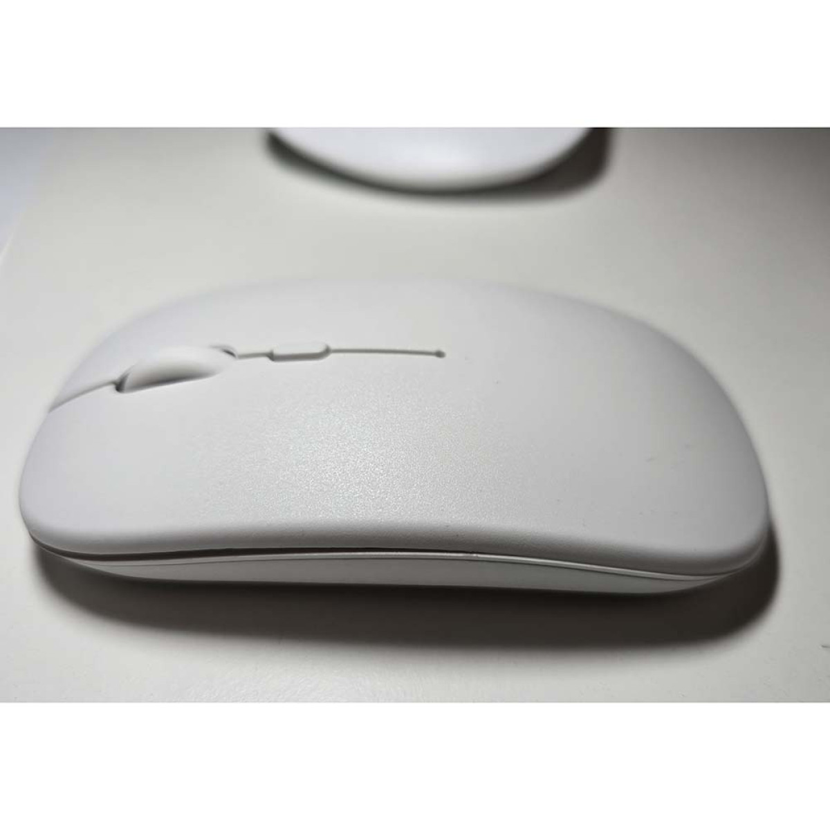 Un mouse per computer bianco con rotellina e pulsanti su una superficie bianca.