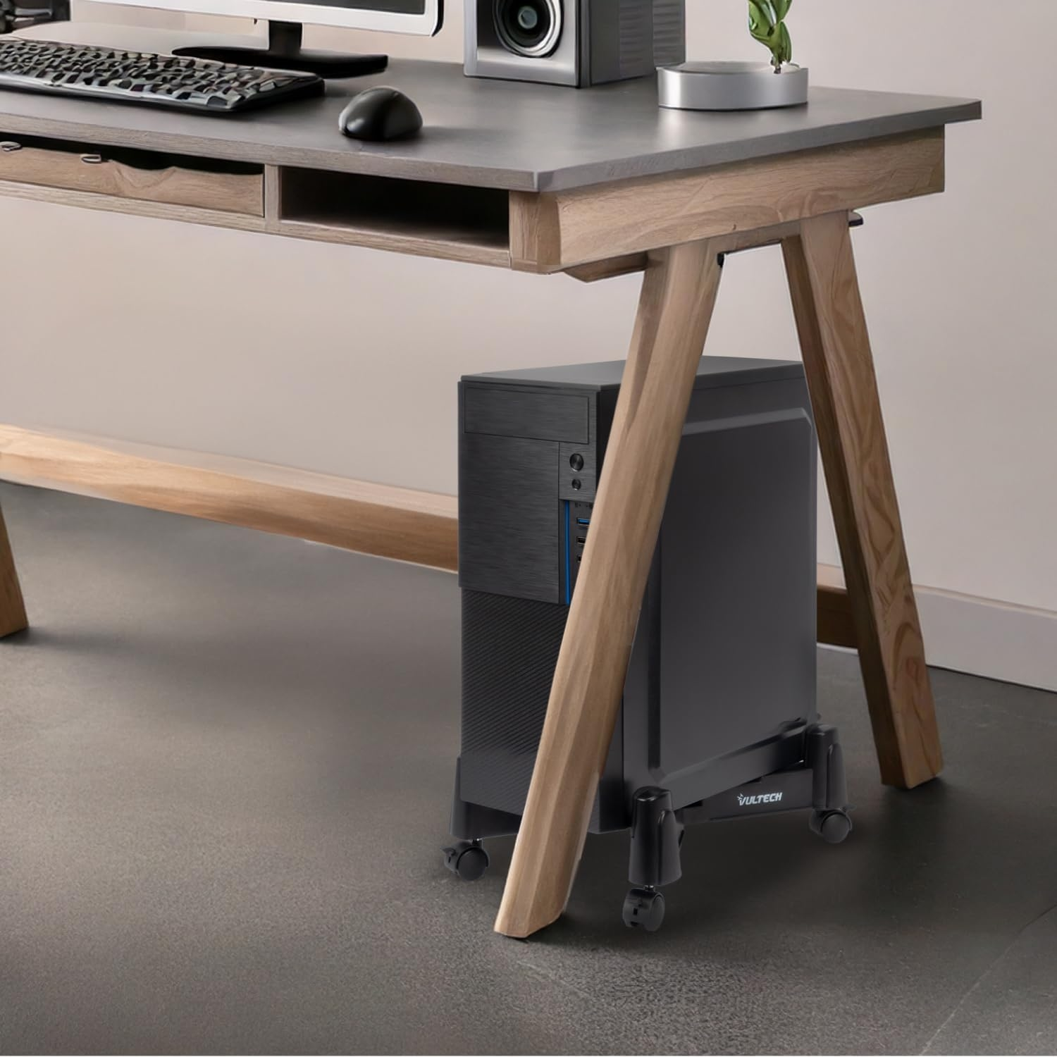Un tower PC nero su un supporto con ruote sotto una scrivania.