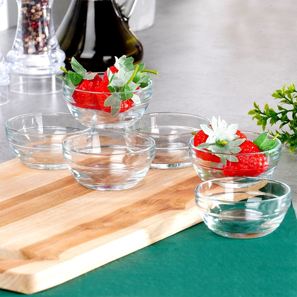 Varios cuencos pequeños de vidrio, algunos con fresas, sobre una tabla de madera.