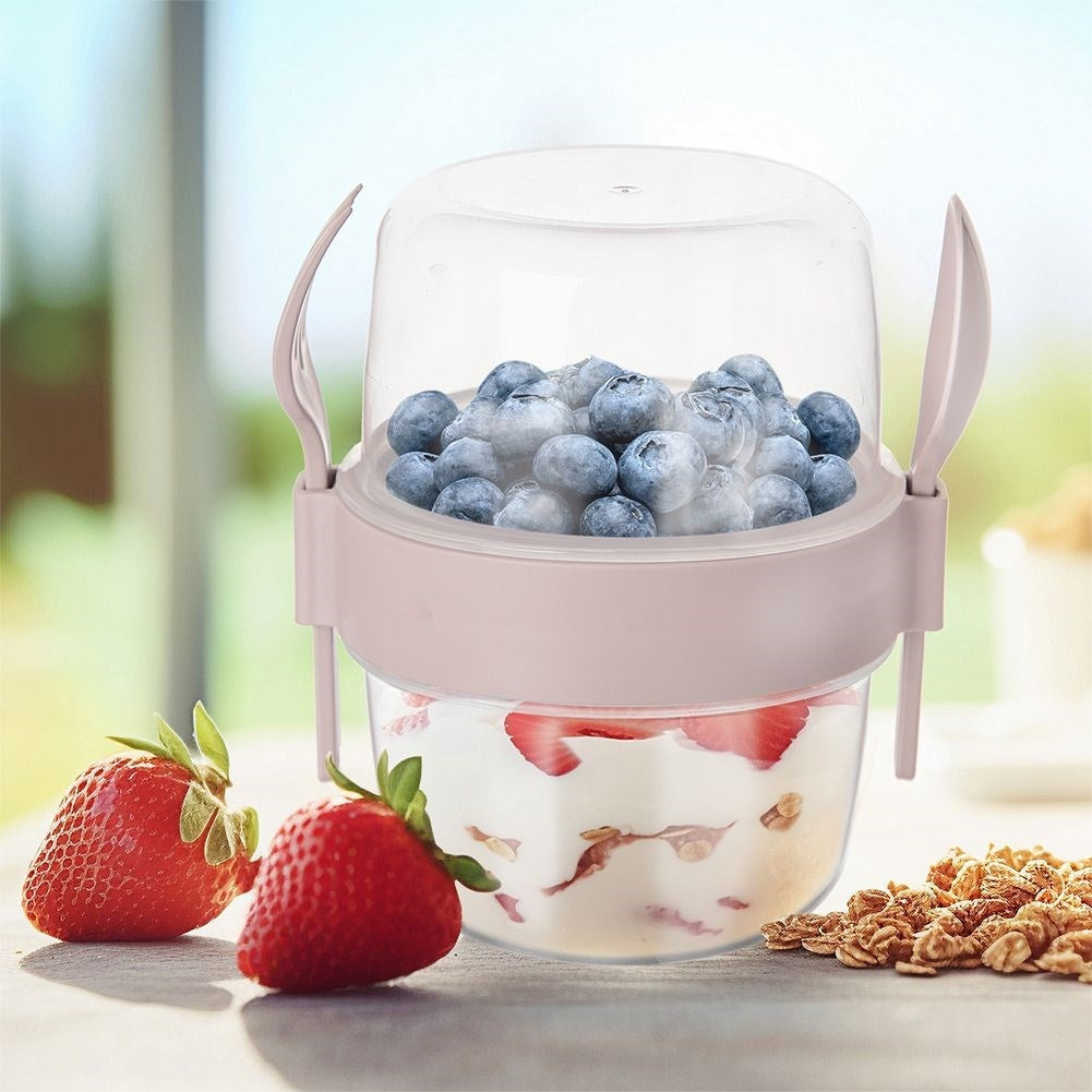 Una taza con yogur, fresas y arándanos, junto a fresas y granola.