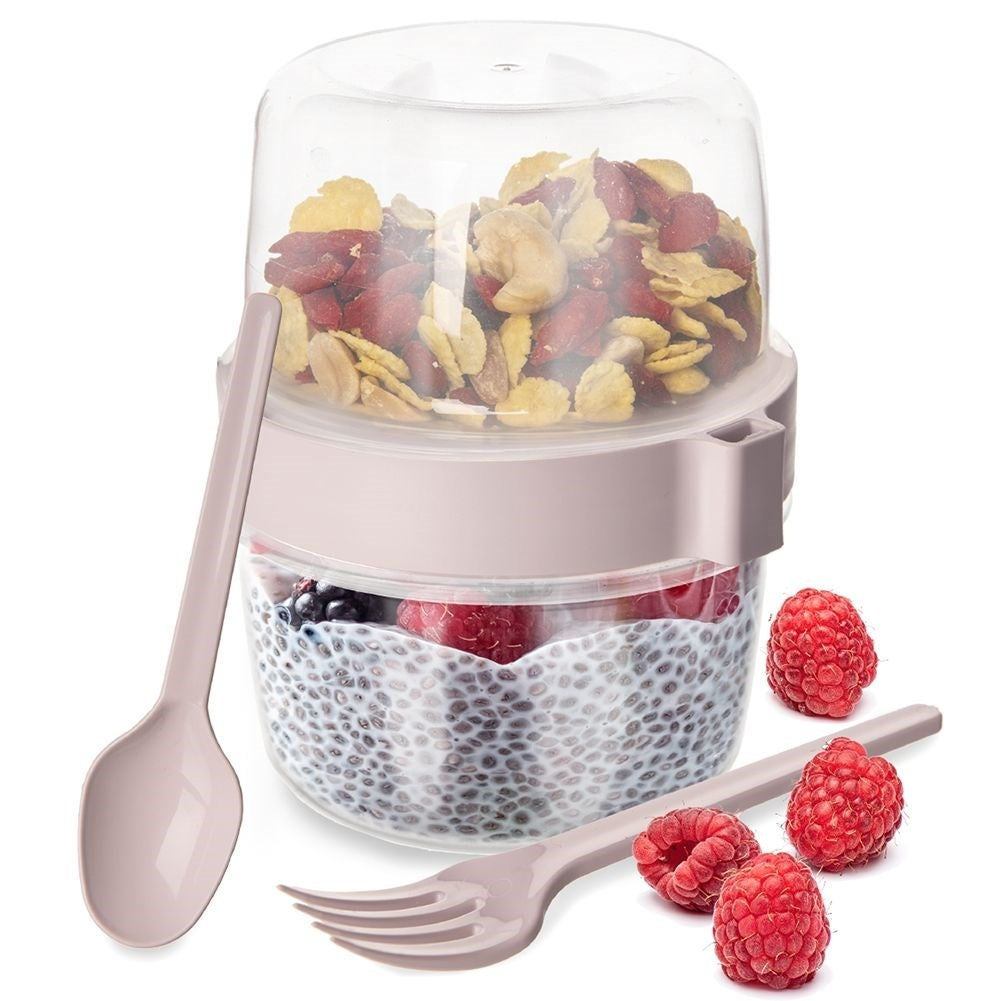 Un recipiente de dos compartimentos con cereales y bayas, con cuchara y tenedor.