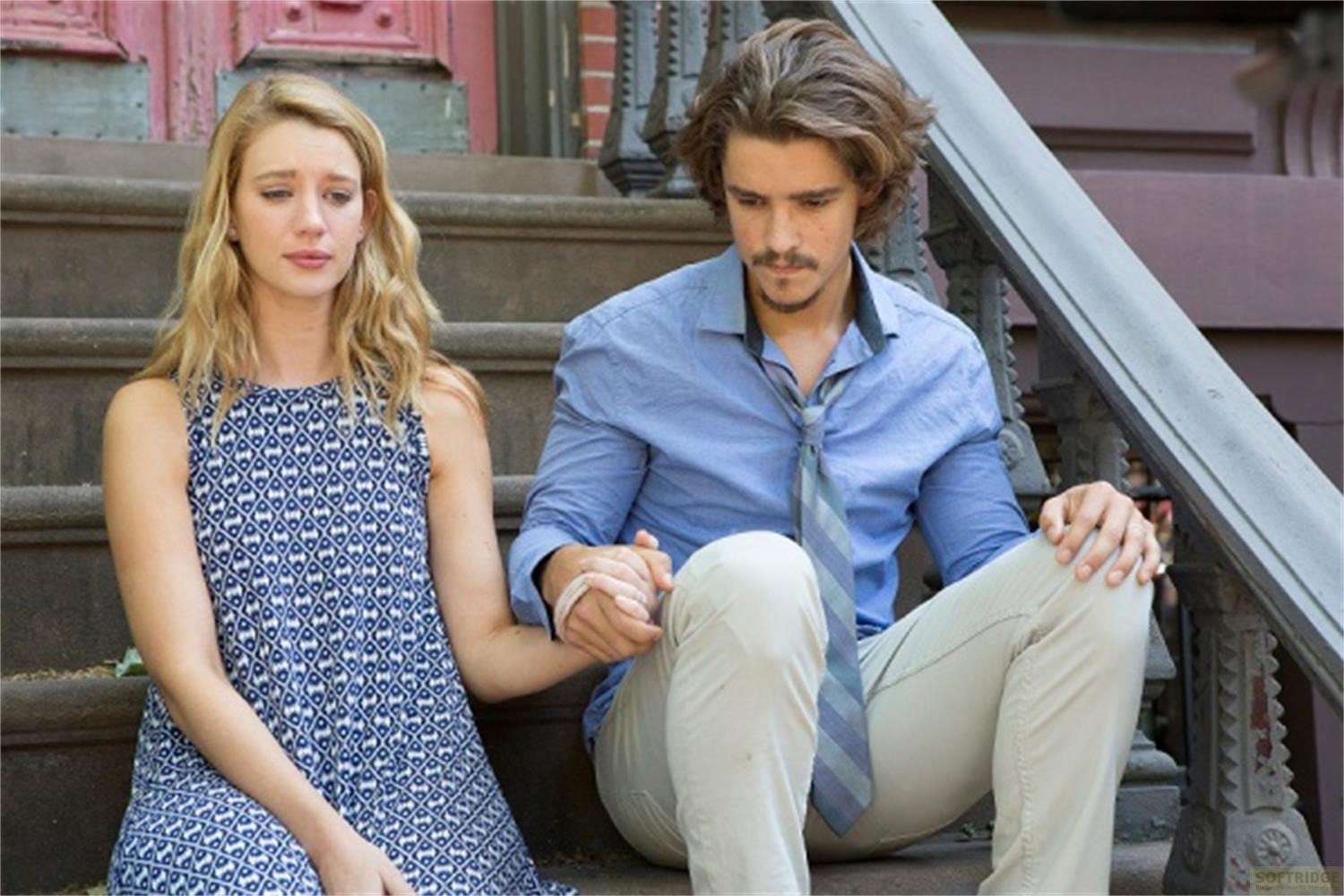 Un homme et une femme assis sur des marches, se tenant la main. Ils ont l'air tristes.