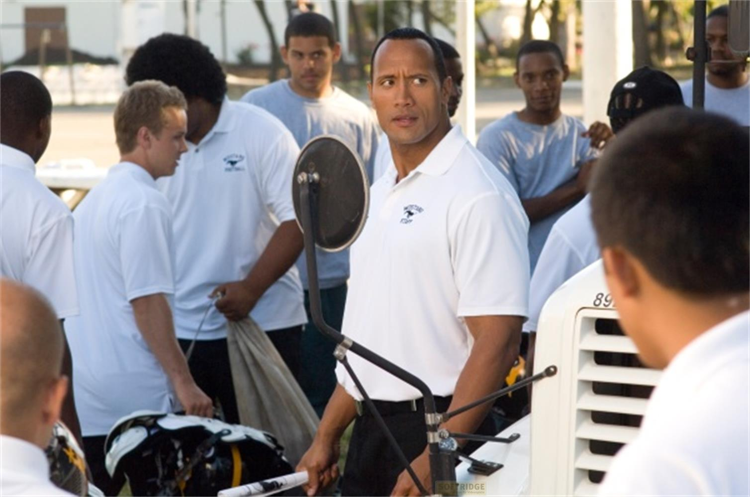 Dwayne Johnson und ein Team in weißen Poloshirts draußen.