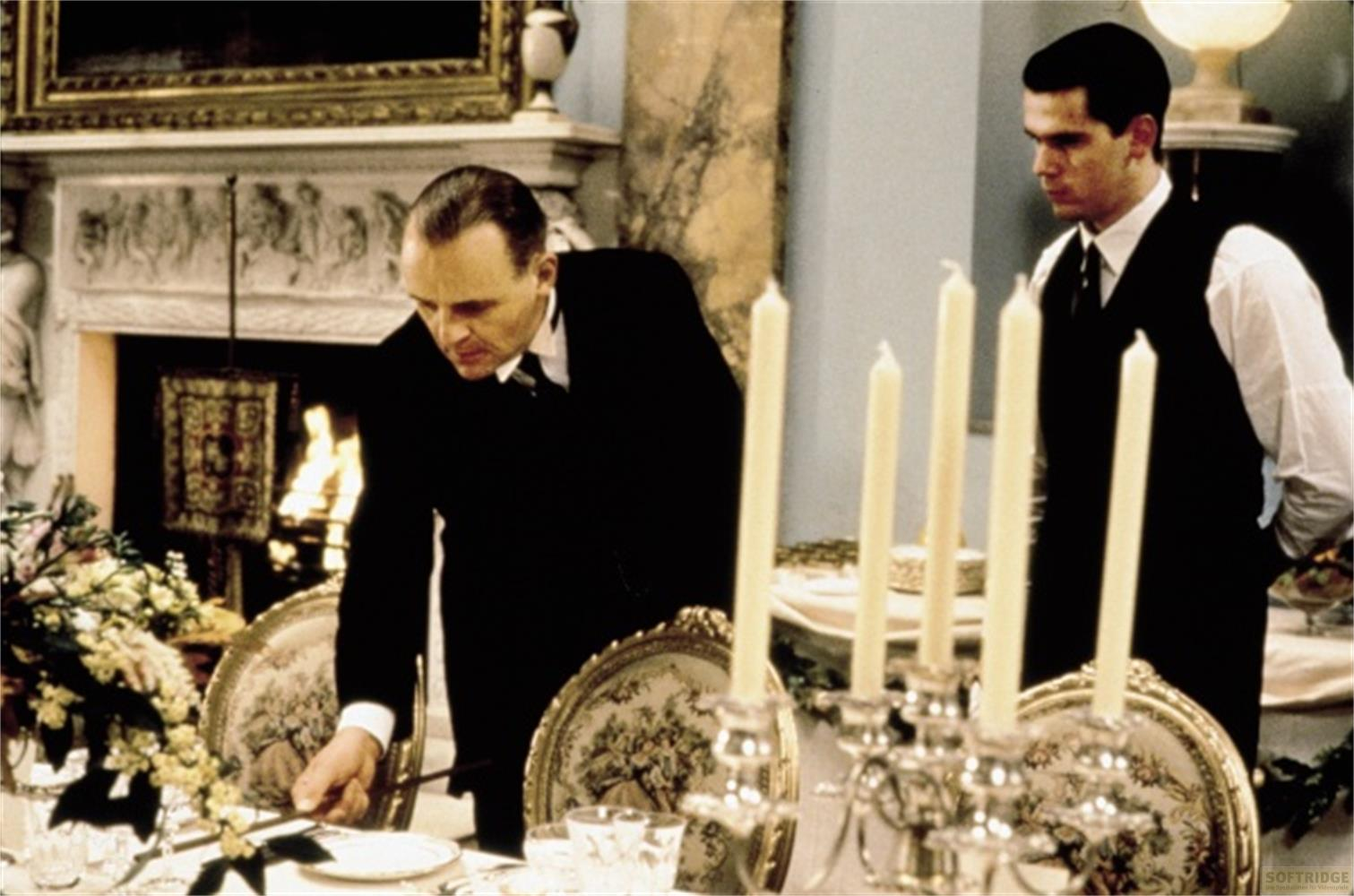 Ein Mann in einem schwarzen Anzug richtet den Tisch, während ein anderer Mann im Hintergrund steht.