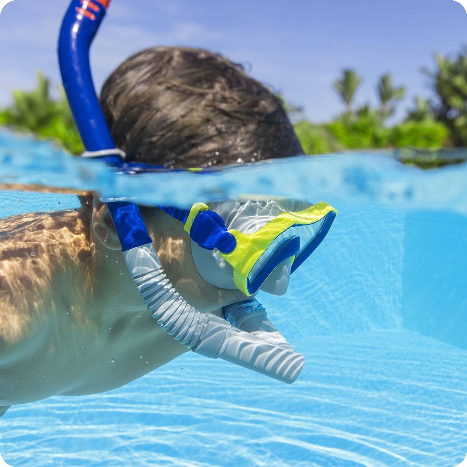 Una persona bucea con esnórquel en una piscina con máscara y tubo azul.
