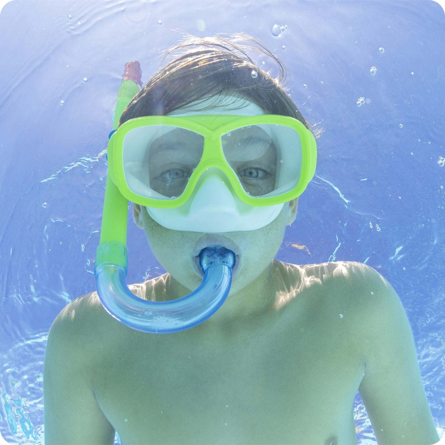 Un niño con máscara de snorkel nada bajo el agua.