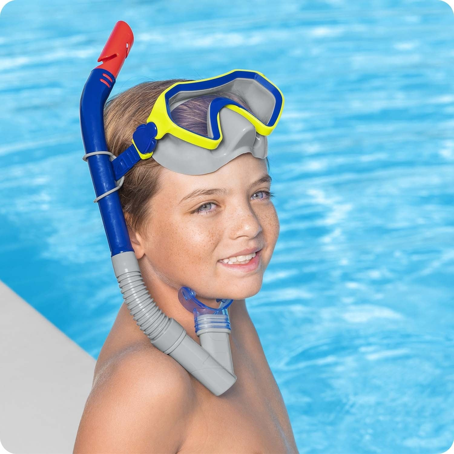 Un niño con máscara y tubo de snorkel junto a la piscina.