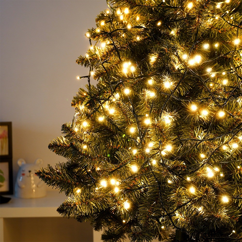 Árbol de Navidad con muchas luces de hadas blancas cálidas, primer plano.