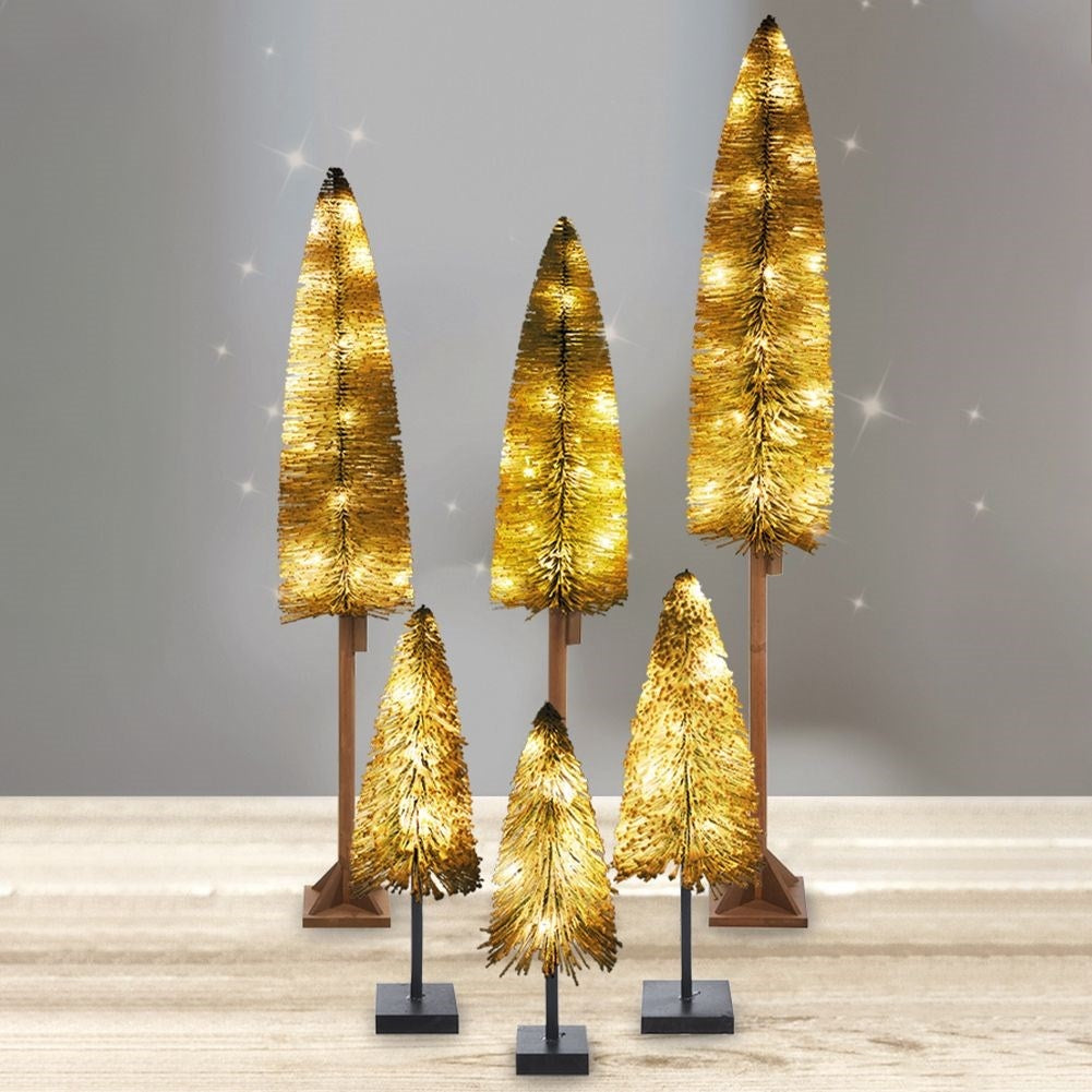 Seis árboles decorativos dorados e iluminados sobre soportes de varios tamaños.