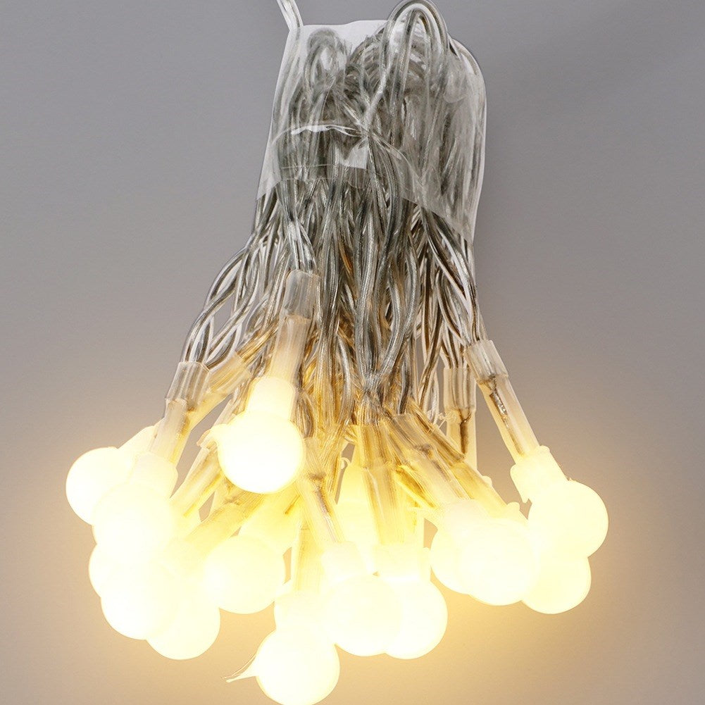 Una cadena de luces LED pequeñas, redondas y de color blanco cálido sujetas por un cable transparente.