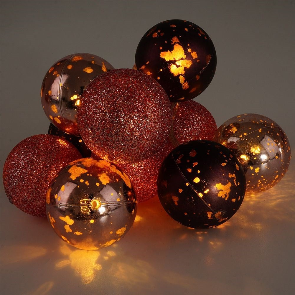 Adornos navideños brillantes en rojo y bronce con motas doradas.