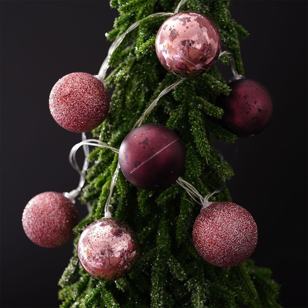 Árbol de Navidad con adornos rojos y rosas y luces.