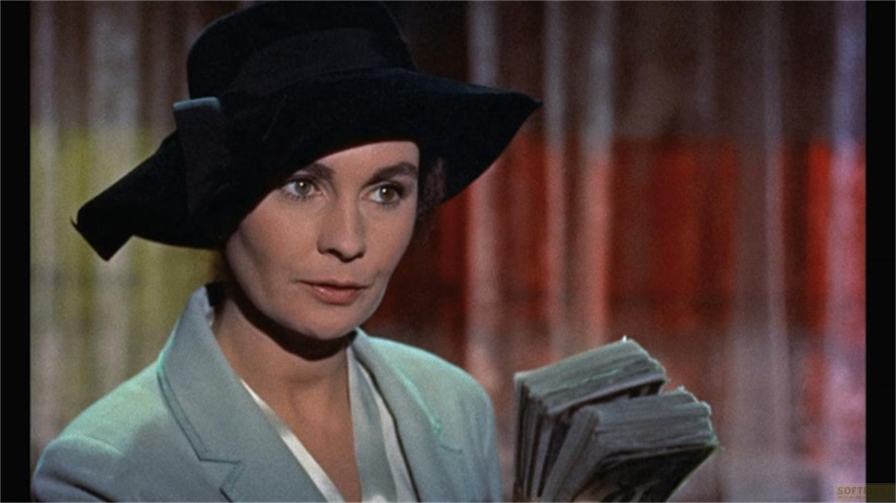 Una donna con cappello nero e blazer azzurro tiene soldi.