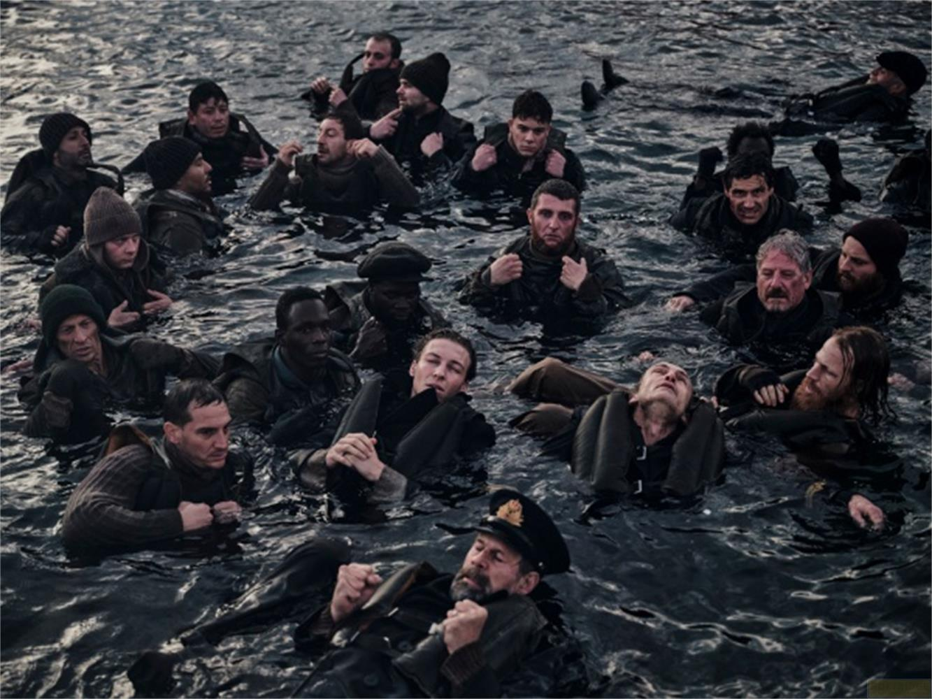 Un gruppo di uomini galleggia in acqua scura, alcuni indossano giubbotti di salvataggio.