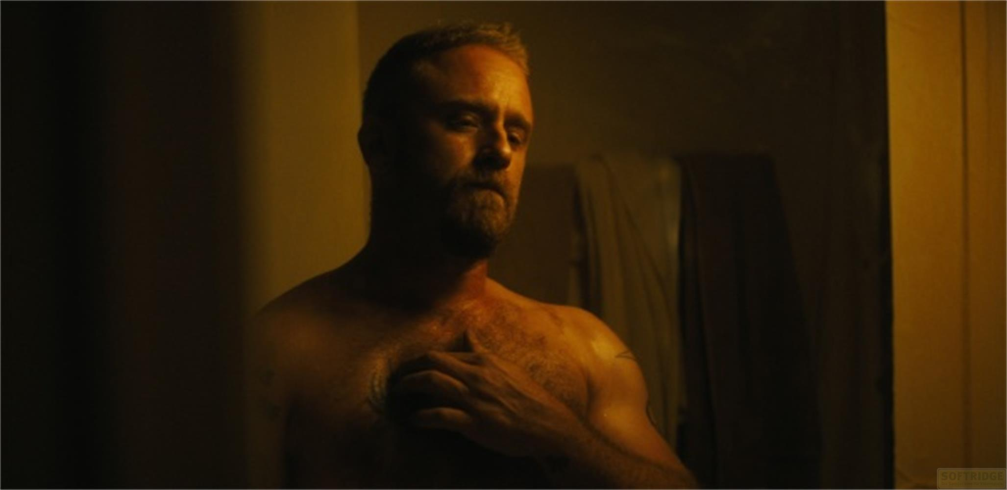 Un uomo con la barba si tocca il petto. È visibile dalle spalle in su.