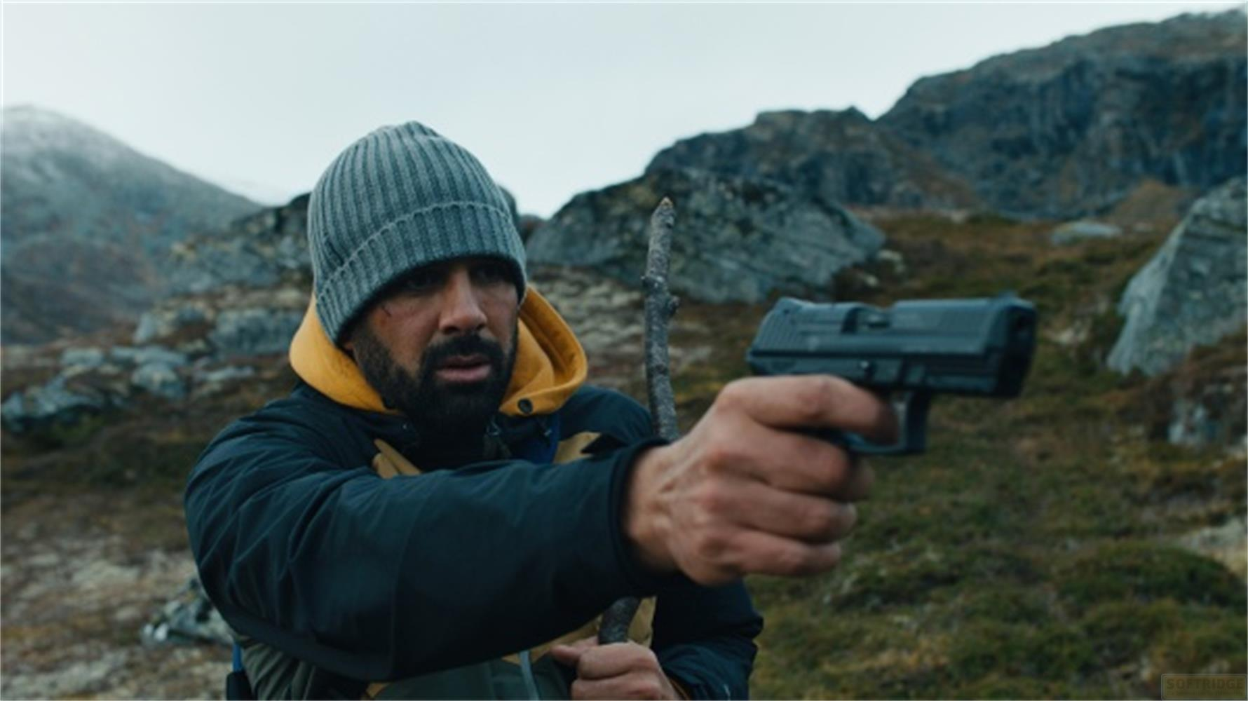 Uomo con pistola in un paesaggio roccioso.