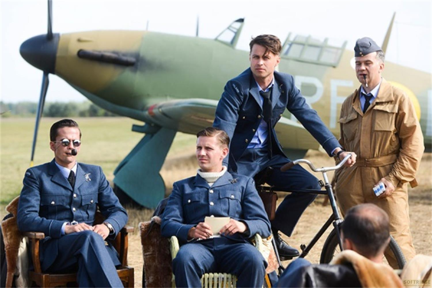 Des hommes en uniforme devant un avion, l'un est assis sur un vélo.