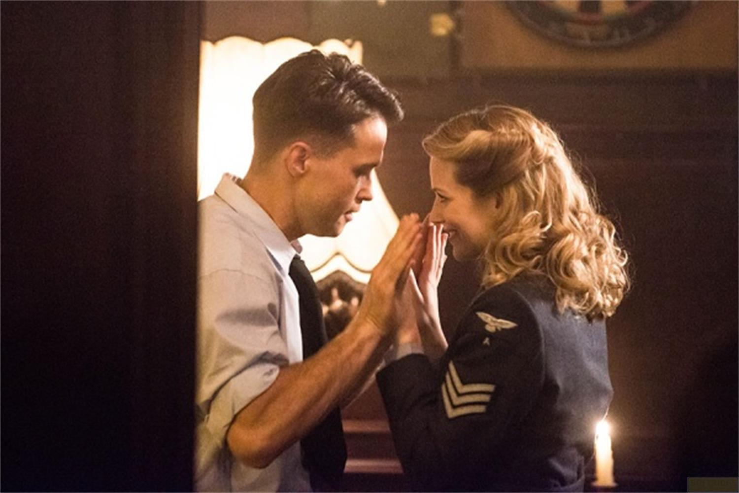 Un homme en chemise claire et cravate tient les mains d'une femme. Elle porte un uniforme sombre.