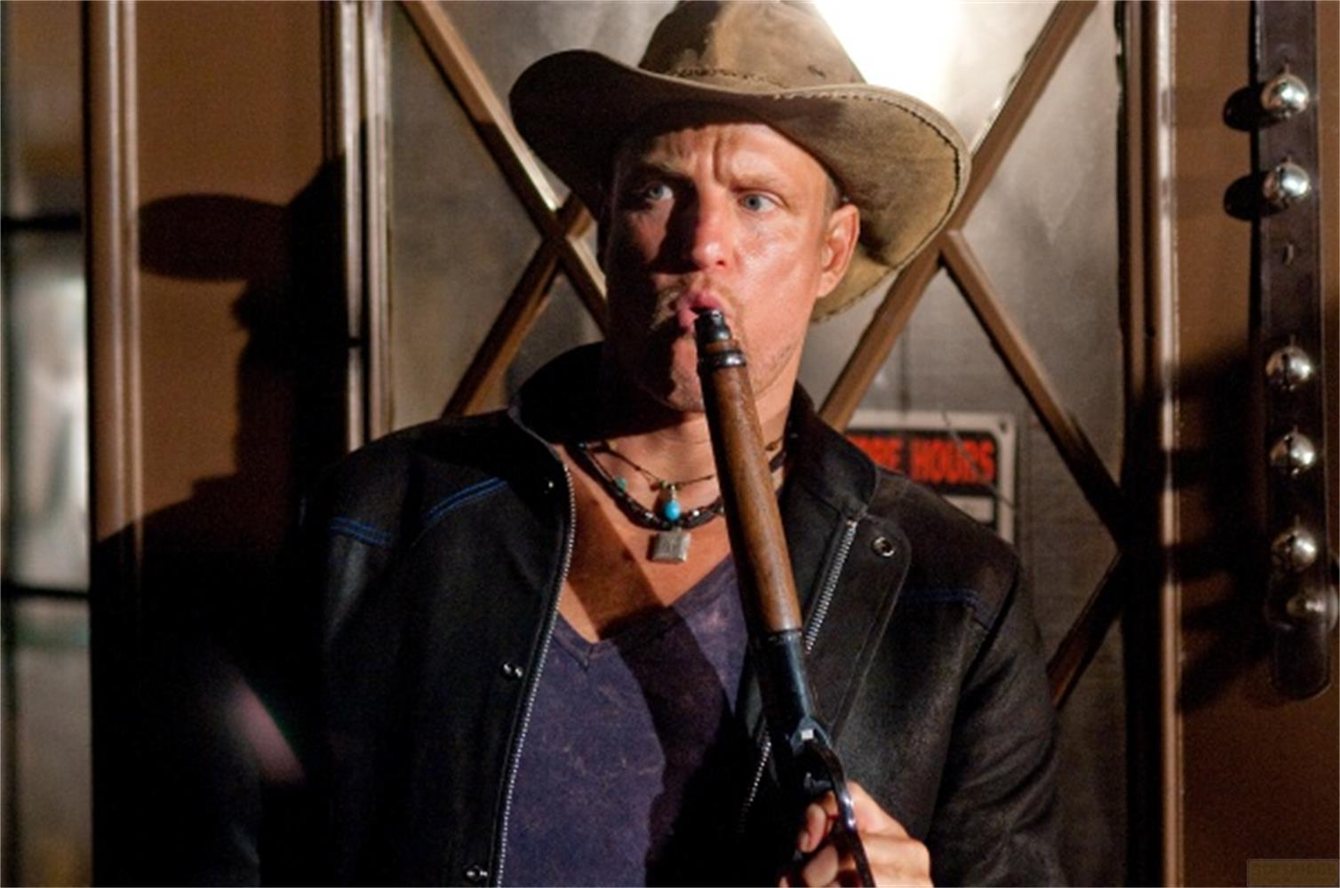 Un homme portant un chapeau de cowboy et une veste en cuir fume une pipe.