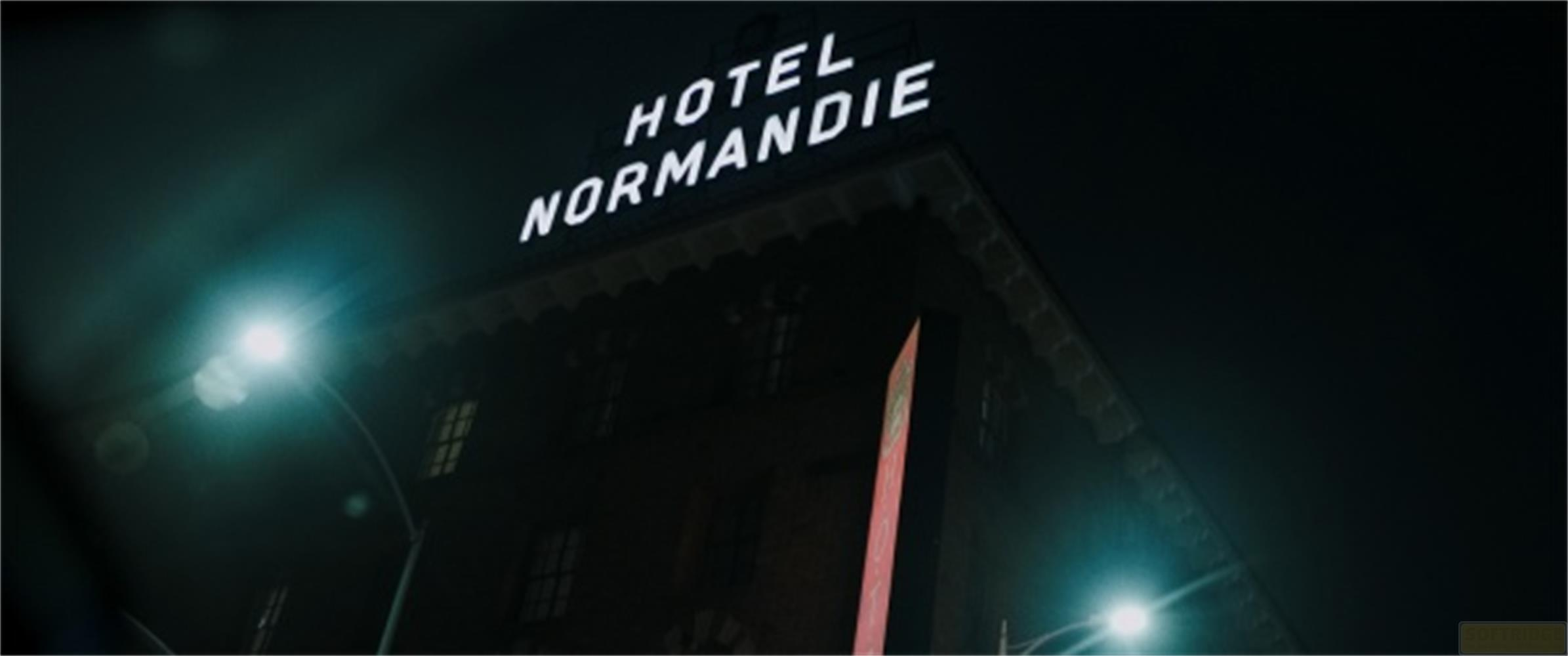 L'insegna dell'Hotel Normandie brilla di notte su un edificio scuro.