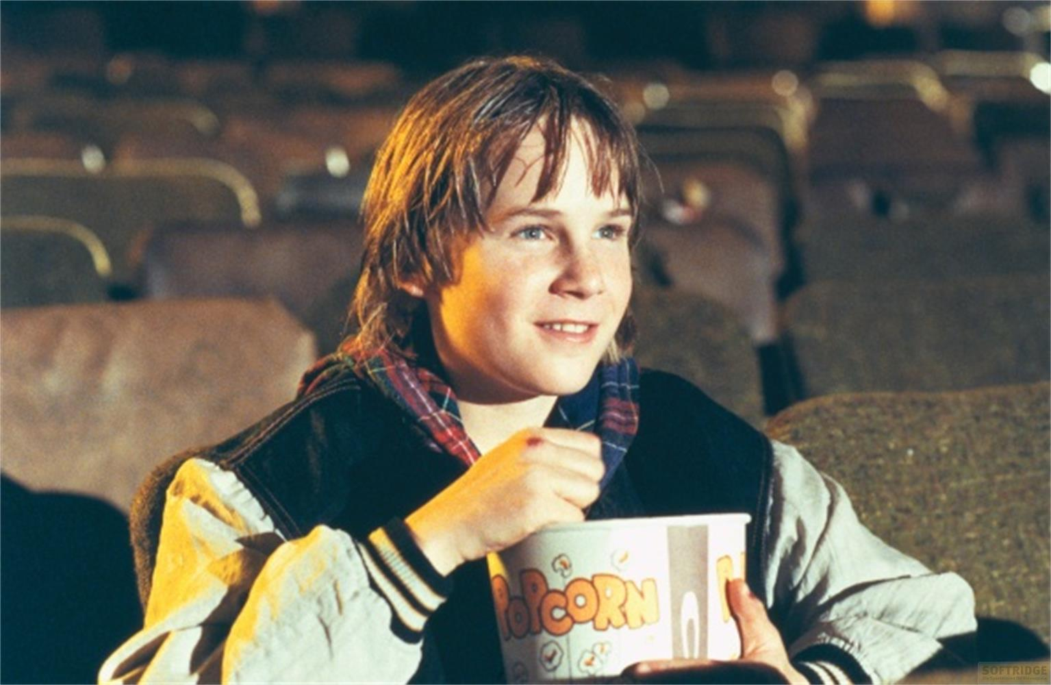 Un ragazzo mangia popcorn al cinema.